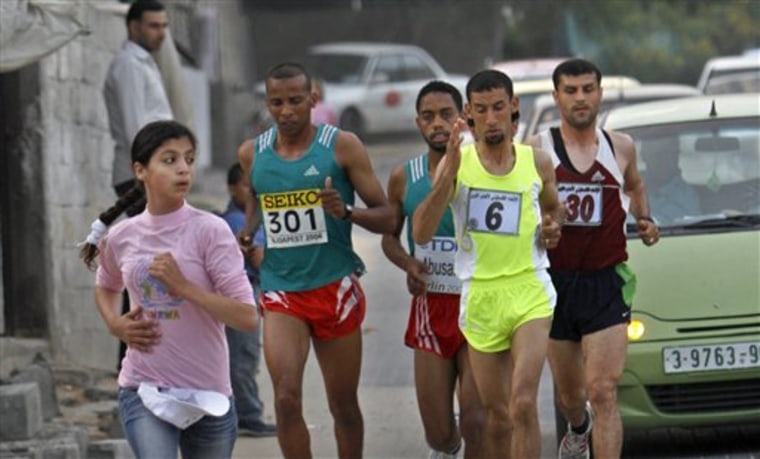 A Palestinian schoolgirl runs in front of participants in the first Gaza marathon from second left,  Husam Naseir, Mahmoud Yousef, Nader Al Masri, Mahmoud Yousef, Omar Abu Said in Beit Lahiya, northern Gaza Strip, Thursday, May 5, 2011. According to UN estimates some 1,500 people attended the event, including children who ran short distances, running the course from Beit Hanoun in the northern Gaza Strip, to Rafah in the south.  (AP Photo/Adel Hana)